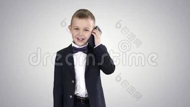 穿着服装的小男孩在渐变背景下散步时打电话。